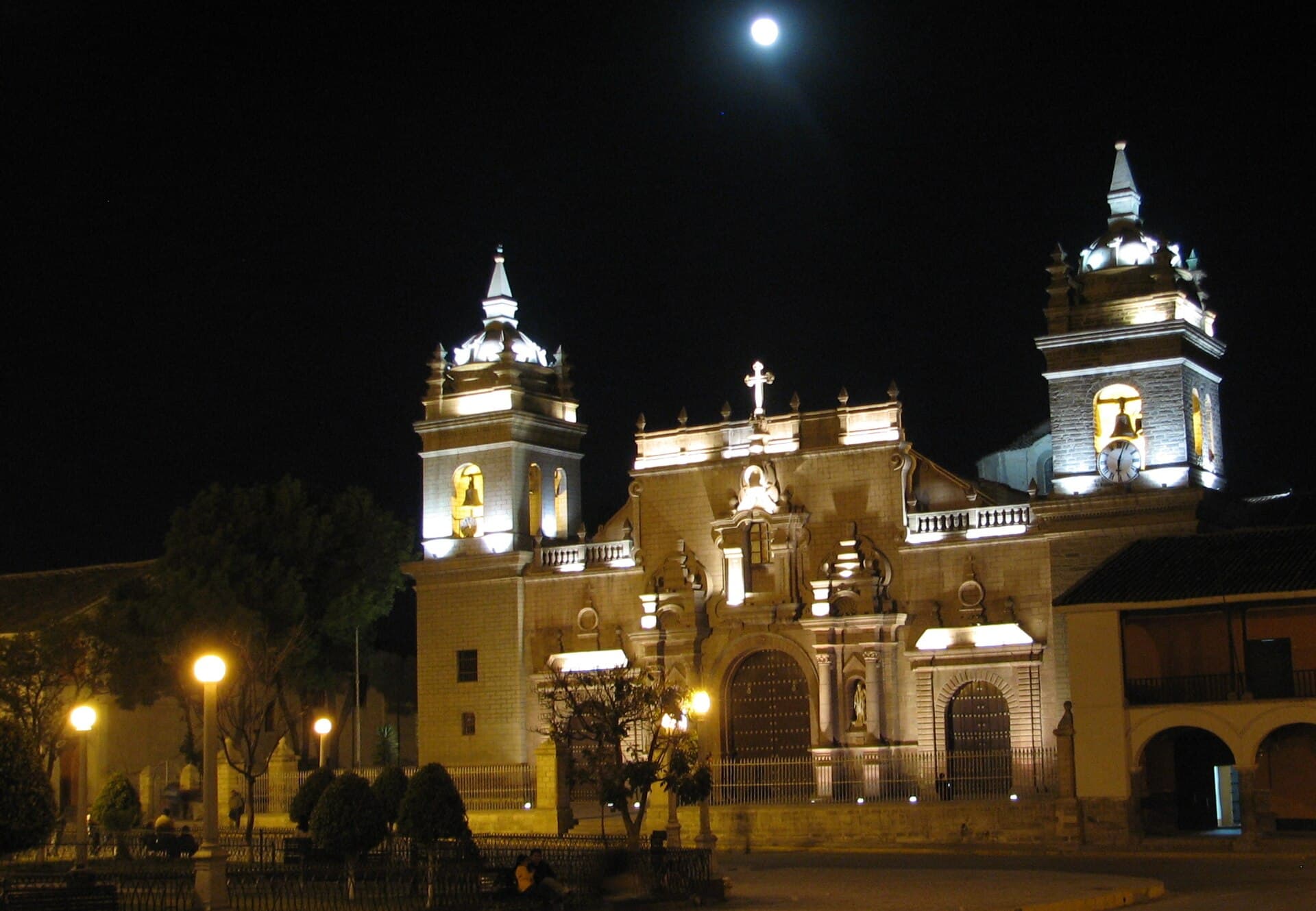 La catedral de Ayacucho iluminada de noche, con la luna llena sobre sus torres